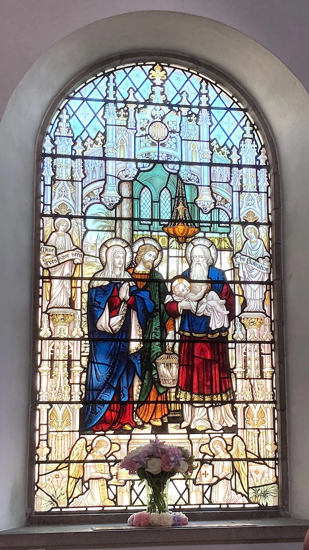 Arched stained glass window showing the Presentation of Jesus in the Temple