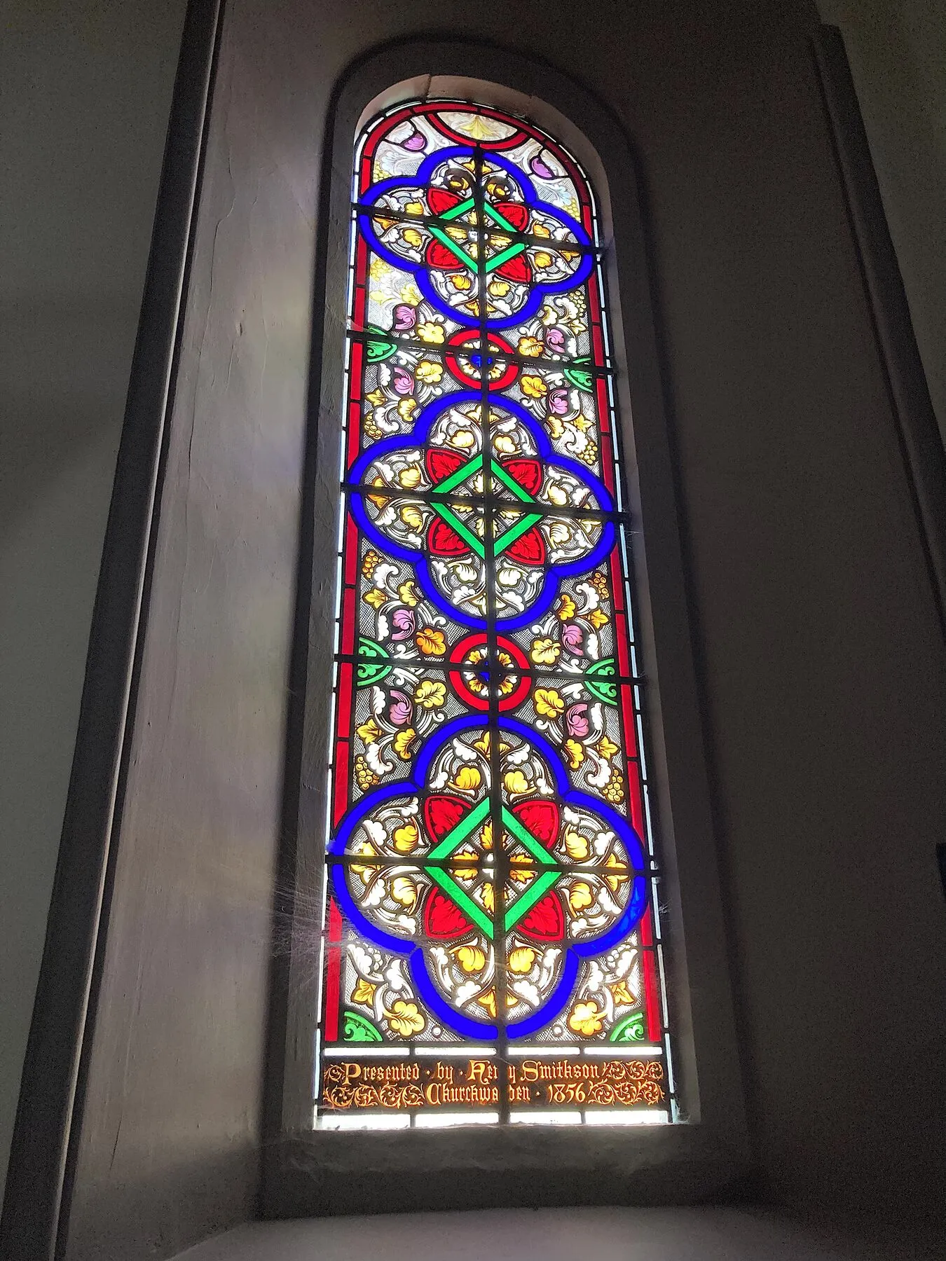 Tall narrow lancet window with red and blue geometric glass