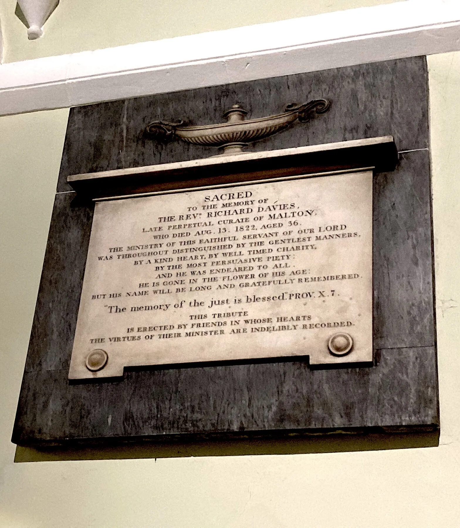 White marble tablet on a dark slate background, topped by a carved lamp