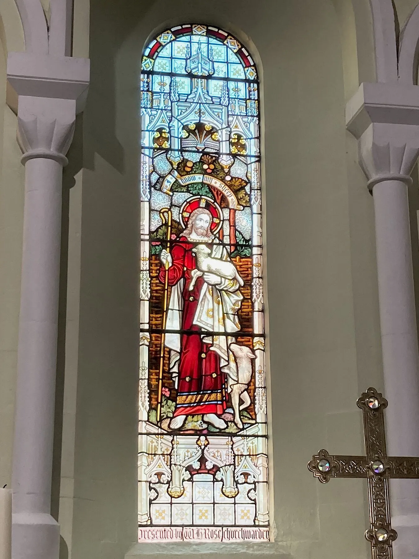 Arched stained glass window with a crowned figure in a red robe