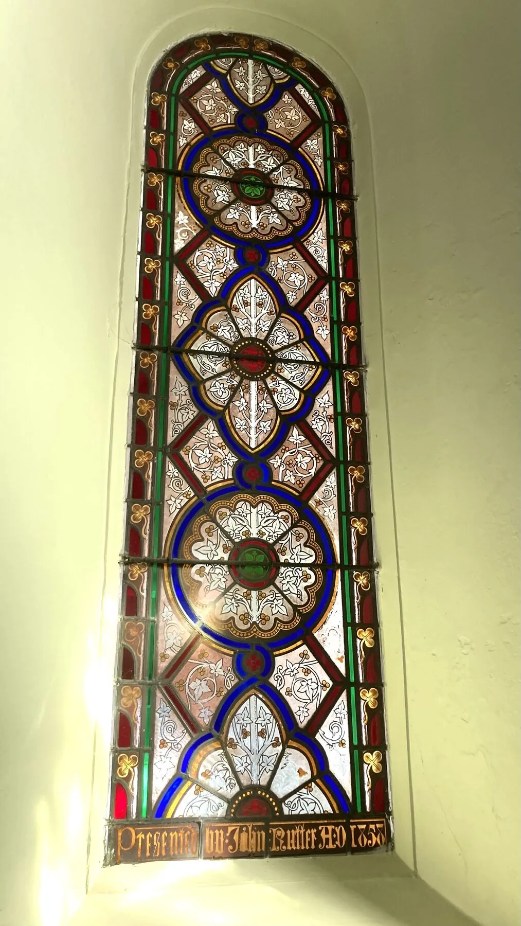 Tall narrow lancet window with rows of circular patterned glass